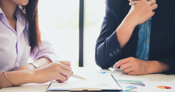 image of two individuals seated at a table going over a document